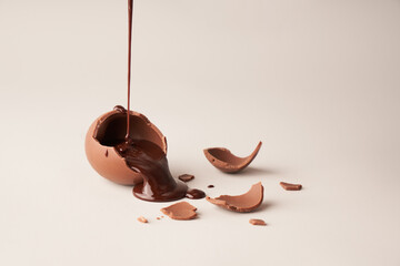 crushed brown chocolate egg with liquid chocolate pour on white background