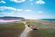 Journey by car to the Koyashskoye Lake in the Crimea. Picturesque view of the sea, the pink lake and the sandy spit between them. On the field road driving cars, in the side of the tourist tent.