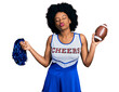 © Krakenimages.com - Young african american woman wearing cheerleader uniform holding pompom and football ball looking at the camera blowing a kiss being lovely and sexy. love expression.