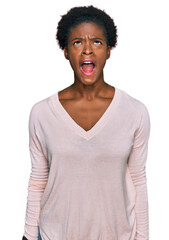 Wall Mural - Young african american girl wearing casual clothes angry and mad screaming frustrated and furious, shouting with anger. rage and aggressive concept.