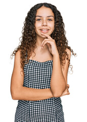 Wall Mural - Teenager hispanic girl wearing casual clothes looking confident at the camera with smile with crossed arms and hand raised on chin. thinking positive.