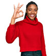 © Krakenimages.com - African american woman wearing casual winter sweater smiling positive doing ok sign with hand and fingers. successful expression.