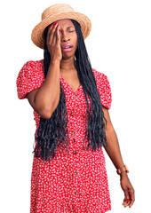 Wall Mural - Young african american woman wearing summer hat yawning tired covering half face, eye and mouth with hand. face hurts in pain.