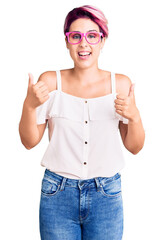 Sticker - Young beautiful woman with pink hair wearing casual clothes and glasses success sign doing positive gesture with hand, thumbs up smiling and happy. cheerful expression and winner gesture.