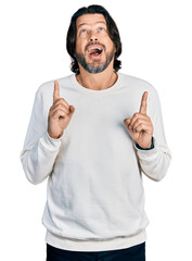 Poster - Middle age caucasian man wearing casual clothes amazed and surprised looking up and pointing with fingers and raised arms.