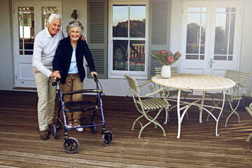 Sticker - Theyll always support each other. Portrait of a smiling senior woman using a walker with her husband beside her outside their home.