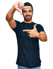 Poster - Young hispanic man wearing casual clothes smiling making frame with hands and fingers with happy face. creativity and photography concept.