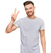 © Krakenimages.com - Young redhead man wearing casual grey t shirt showing and pointing up with fingers number two while smiling confident and happy.