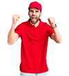 © Krakenimages.com - Young handsome man with beard wearing delivery uniform angry and mad raising fists frustrated and furious while shouting with anger. rage and aggressive concept.