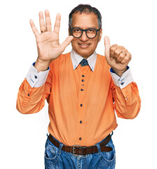 Canvas Print - Middle age indian man wearing casual clothes and glasses showing and pointing up with fingers number six while smiling confident and happy.