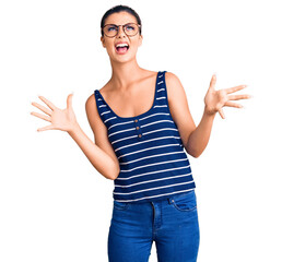 Sticker - Young beautiful woman wearing casual clothes and glasses crazy and mad shouting and yelling with aggressive expression and arms raised. frustration concept.