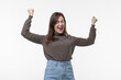 © Регина Ерофеева - Yes finally success. Positive woman raises arms with clenched fists celebrates something has upbeat mood feels euphoric wears a casual turtleneck and jeans, isolated on a white background