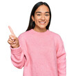 © Krakenimages.com - Young asian woman wearing casual winter sweater pointing finger up with successful idea. exited and happy. number one.