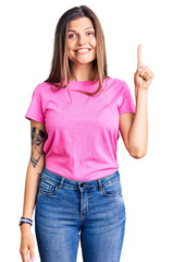 Wall Mural - Beautiful caucasian woman wearing casual clothes showing and pointing up with finger number one while smiling confident and happy.