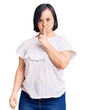 © Krakenimages.com - Brunette woman with down syndrome wearing casual white tshirt asking to be quiet with finger on lips. silence and secret concept.