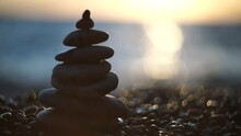 Balanced Rock Pyramid On Pebbles Beach. Golden Sea Bokeh On Background. Selective Focus, Zen Stones On Sea Beach, Meditation, Spa, Harmony, Calm, Balance Concept.