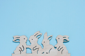 Wall Mural - Flat wooden craft blank in shape of bunnies on pastel blue background. Happy Easter concept. Mockup for greeting card with space for text. top view, flat lay