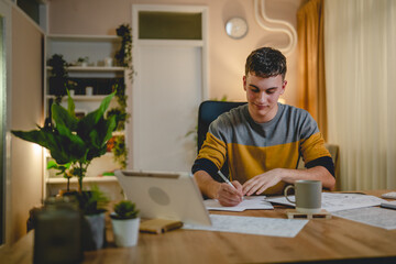 Young caucasian man teenager student study at home at the table night