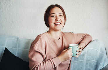 Poster - Home is my favourite place to be. Cropped portrait of an attractive young woman sitting on her sofa alone and holding a cup of coffee at home.