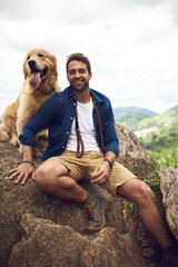 Wall Mural - We just love hiking through the mountain. Cropped portrait of a handsome young man and his dog taking a break during a hike in the mountains.