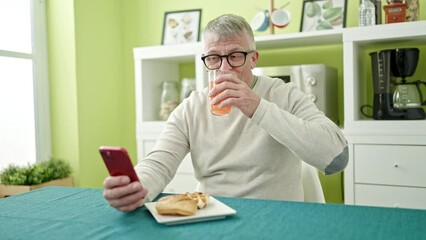 Sticker - Middle age grey-haired man having breakfast using smartphone at home