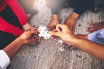 Poster - Finding solutions piece by piece. Shot of a group of unidentifiable businesspeople building a puzzle together.