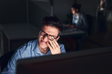 Leinwandbilder - This headache is not helping my productivity. Shot of a young businessman working late at night in a modern office.