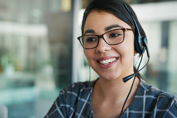 Canvas Print - Shes a delight to speak to. Shot of a happy young woman using a headset at work.