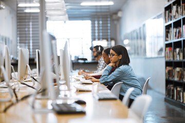 The student life. Shot of a group of university students working on computers in the library at campus.