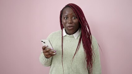 Poster - African woman with braided hair smiling holding money and smartphone over isolated pink background