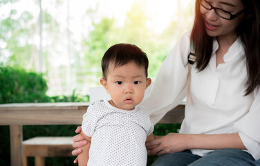 Young mother with daughter sitting in chair at park