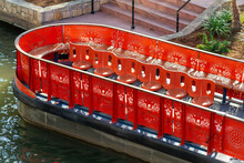 Red Tour Boat In The Canals Of San Antonio Texas In Late Afternoon Shade In River With Steps And Cement Embankment