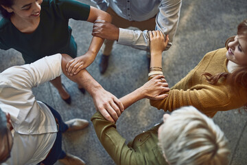 Aufkleber - Behind a successful business is a strong team. High angle shot of a group of colleagues linking arms in solidarity at work.