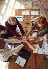 Wall Mural - Do it together and everybody wins. High angle shot of a group of colleagues joining their hands in solidarity during a meeting in a modern office.