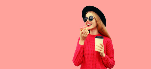 Portrait of modern young woman eating donut drinking coffee isolated on pink background