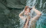Fototapeta  - beautiful young cute sexy redhead woman enjoying relaxed the splashing water of the waterfall in the Spa Wellness, feels the falling water