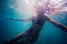Underwater Image Of Woman Floating, Surrounded By Bubbles.