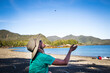 © Cavan Images - HAIDA GWAII, BRITISH COLUMBIA, CANADA. A woman sits on an empty beach and tosses a raisin into the air to catch with her mouth.