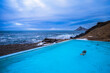 © Cavan Images - A woman swiming in a geo thermal heated pool on the beach near Nordurfjordur, Iceland