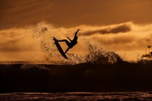 Surfer Taking Flight On A Wave Into The Evening Light
