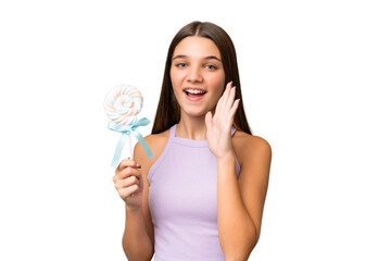 Sticker - Teenager caucasian girl holding a lollipop over isolated background shouting with mouth wide open