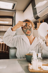 Wall Mural - One beautiful middle age woman smile and do beauty care mask daily treatment on her face inside a camper van motor home. Alternative natural lifestyle female people alone. Travel and skin care concept