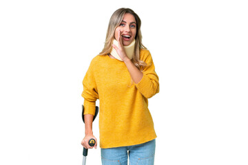 Young Uruguayan woman wearing neck brace and crutches over isolated background whispering something