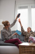 © astrosystem - Mother having trouble with a lazy teenager girl at home while playing video games on a smartphone.