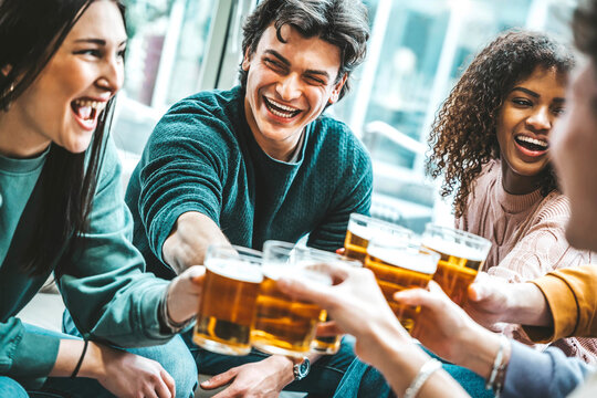 happy multiracial friends toasting beer glasses at brewery pub restaurant - group of young people en