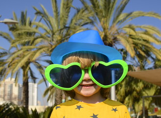 a cute boy in large glasses in the shape of a heart. the child rejoices in the holiday. concept: mot