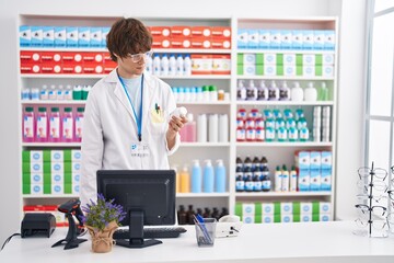 Sticker - Young blond man pharmacist using computer holding pills bottle at pharmacy