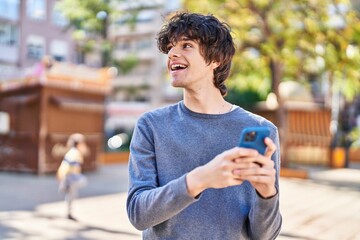 Sticker - Young hispanic man smiling confident using smartphone at park