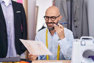 Poster - Young bald man tailor talking on smartphone looking clothing design at tailor shop