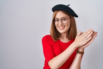 Sticker - Young redhead woman standing wearing glasses and beret clapping and applauding happy and joyful, smiling proud hands together